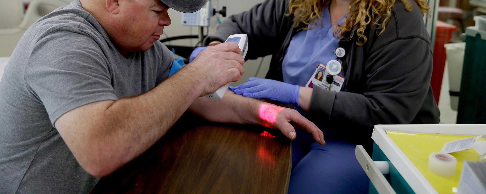 Brian Madeux, de 44 anos, usa um dispositivo infravermelho para visualizar suas veias enquanto a enfermeira Siobhan Field prepara um acesso intravenoso para a primeira terapia de edição genética em humanos, no UCSF Benioff Children's Hospital Oakland, em Oakland, Califórnia, 6 de novembro de 2017 - Sputnik Brasil, 1920, 07.10.2026