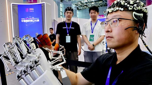 Um membro da equipe de Interface Cérebro-Computador e Reabilitação Inteligente da Universidade de Yanshan demonstra uma mão robótica vestível, controlada pelo cérebro, voltada para a reabilitação ativa, durante a 4ª Competição de Interface Cérebro-Computador da China, realizada no Centro Internacional de Comércio de Tecnologia de Zhongguancun, em Pequim, China, 26 de julho de 2026 - Sputnik Brasil