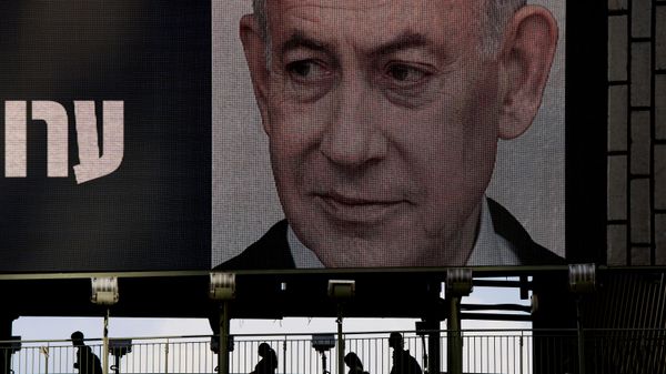 Pessoas cruzam ponte em frente a outdoor com o rosto do primeiro-ministro de Israel, Benjamin Netanyahu, em Ramat Gan, em 18 de outubro de 2026 - Sputnik Brasil
