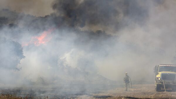 A firefighter is dwarfed by a burning mountain at the 6,500 acre Border Fire in eastern San Diego County, California, in the late afternoon on June 22, 2016. - Sputnik Brasil