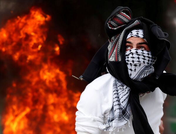 Um manifestante palestino atira uma pedra contra os soldados israelenses na Cisjordânia, em 20 de dezembro de 2017, durante os protestos populares contra a decisão de Donald Trump de reconhecer Jerusalém como a capital de Israel - Sputnik Brasil