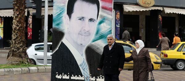 Sírios passeando perto do retrato do presidente do país, Bashar Assad - Sputnik Brasil