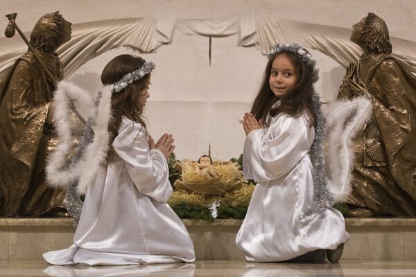 Meninas vestidas de anjos rezam perto do altar na noite de Natal, Kosovo - Sputnik Brasil