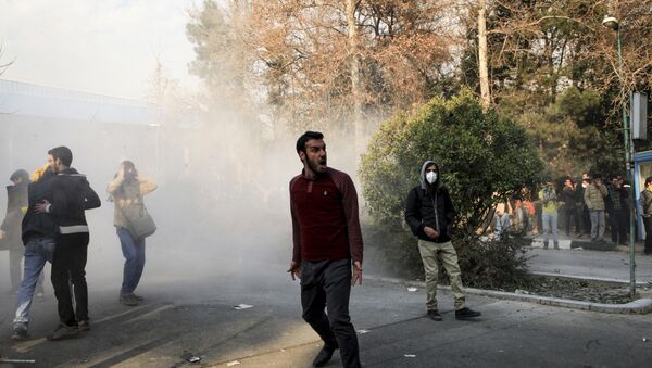 Iran, university students attend a protest inside Tehran University while a smoke grenade is thrown by anti-riot Iranian police, in Tehran, Iran, Saturday, Dec. 30, 2017 - Sputnik Brasil