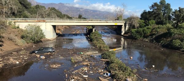 An abandoned car is seen stuck in flooded water on the 101 freeway after a mudslide in Montecito, California, U.S. January 10, 2018 - Sputnik Brasil