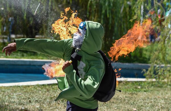 Manifestante lança um coquetel Molotov em um policial durante os confrontos em Caracas, na Venezuela - Sputnik Brasil