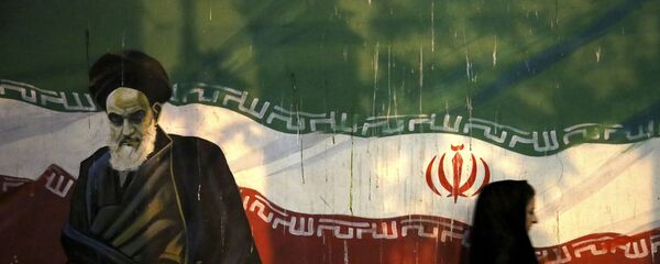 Iraniana coberta passa por muro que retrata o revolucionário aiatolá Khomeini e a bandeira iraniana nacional, pintada na parede da antiga embaixada dos EUA, em Teerã, Irã - Sputnik Brasil
