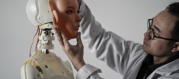 Engenheiro segurando um rosto de silicone diante de um robô na fábrica da EXDOLL - Sputnik Brasil