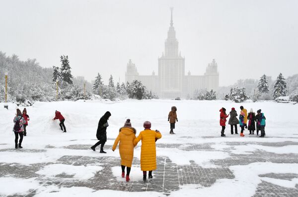 Turistas passeiam durante nevada na calçada em frente ao edifício da Universidade Estatal de Moscou, nas Colinas Vorobyovy - Sputnik Brasil