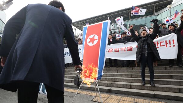 Membro do grupo civil sul-coreano queimando a bandeira nacional da Coreia do Norte durante a manifestação contra participação de Pyongyang nos Jogos Olímpicos em PyeongChang - Sputnik Brasil