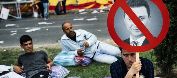 Protestos na Macedônia. Um manifestante empunha o pequeno cartaz com uma foto de premeiro-ministro macedônio Nikola Gruevski durante o protesto antigovernamental no centro de Skopje no 17 de maio de 2015. Mais de 20.000 pessoas se reuniram na capital da Macedónia para exigir a renúncia do governo do primeiro-ministro Nikola Gruevski, que é responsavel pela crise política profunda e um surto de violência no país. - Sputnik Brasil
