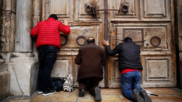 Fiéis se ajoelham e rezam em frente às portas fechadas da Igreja do Santo Sepulcro na Cidade Velha de Jerusalém, 25 de fevereiro de 2018 - Sputnik Brasil