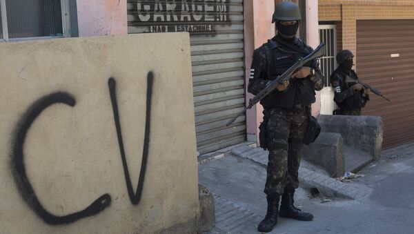 Militar na Rocinha ao lado de muro com as inscrições do Comando Vermelho. - Sputnik Brasil