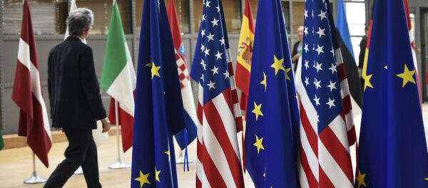 Um homem caminha perto das bandeiras dos EUA e UE na sede da União Europeia, em 15 de Maio de 2017. - Sputnik Brasil