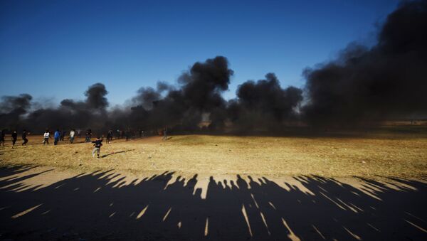 Manifestantes palestinos durante os confrontos com soldados israelenses na fronteira entre a Faixa de Gaza e Israel - Sputnik Brasil