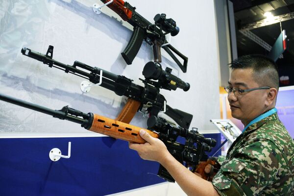 Visitante da exposição na Malásia observando armas de fogo de produção bielorrussa - Sputnik Brasil