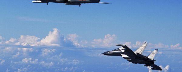 Caça Su-30 do Exército Popular de Libertação da China (à direita) voando perto do bombardeiro H-6K durante manobras no mar da China Oriental - Sputnik Brasil
