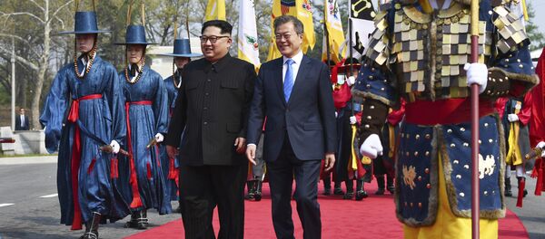 O líder norte-coreano, Kim Jong-un, à esquerda, e  o líder sul-coreano, Moon Jae-in, à direita, caminham juntos na fronteira do vilarejo de Panmunjom, zona desmilitarizada, 27 de abril de 2018 - Sputnik Brasil