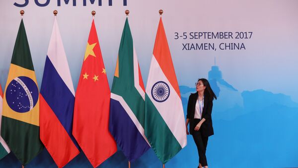 A staff worker walks past the national flags of Brazil, Russia, China, South Africa and India before a group photo during the BRICS Summit at the Xiamen International Conference and Exhibition Center in Xiamen, southeastern China's Fujian Province, China September 4, 2017 - Sputnik Brasil