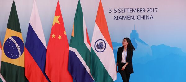 Uma das organizadoras da cúpula dos BRICS lado das bandeiras dos países-membros da organização. - Sputnik Brasil