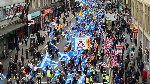 Anti-independence supporters wave Union Jack flags (R) as thousands of demonstrators carry Saltire flags, the national flag of Scotland, as they march in support of Scottish independence through the streets of Glasgow, on May 5, 2018 - Sputnik Brasil