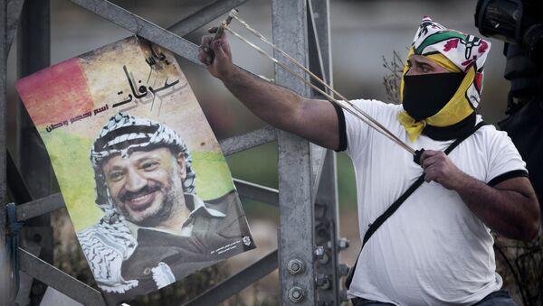 Manifestante palestino usa estilingue para atirar pedras contra forças de segurança israelenses durante confrontos após um protesto para marcar o 11º aniversário da morte do líder palestino Yasser Arafat, na cidade de Ramallah, Cisjordânia, 11 de novembro de 2015. - Sputnik Brasil