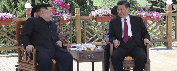 Presidente chinês, Xi Jinping (à direita), falando com o líder norte-coreano, Kim Jong-un (à esquerda) em Dalian, China - Sputnik Brasil