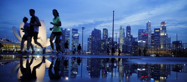 Joggers run past as the skyline of Singapore's financial district is seen in the background - Sputnik Brasil