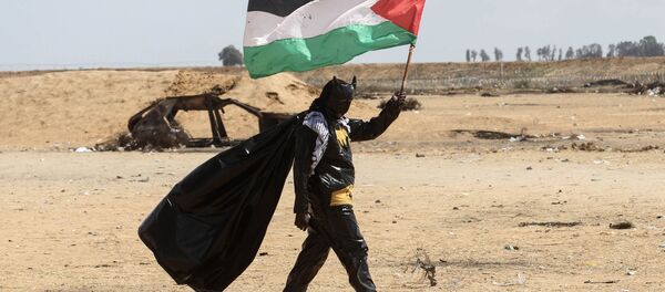 Manifestante palestino vestido de Batman segura a bandeira nacional perto da fronteira entre Israel e Faixa de Gaza Manifestante palestino vestido de Batman segura a bandeira nacional perto da fronteira entre Israel e Faixa de Gaza - Sputnik Brasil