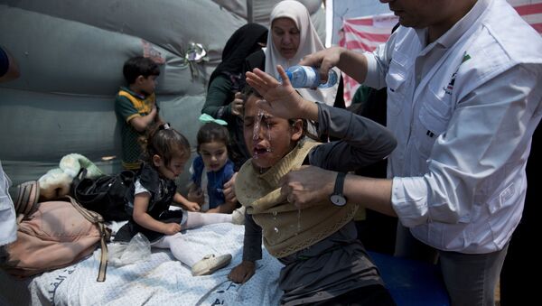 Medics treat Palestinian children suffering from teargas inhalation during a protest near Beit Lahiya, Gaza Strip, Monday, May 14, 2018 - Sputnik Brasil