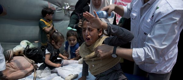 Medics treat Palestinian children suffering from teargas inhalation during a protest near Beit Lahiya, Gaza Strip, Monday, May 14, 2018 - Sputnik Brasil