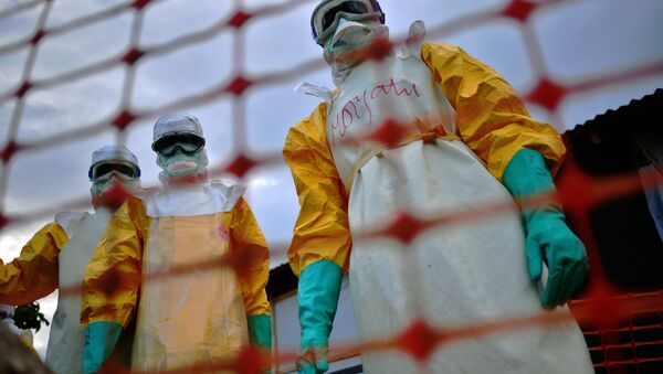 Uma foto de arquivo tirada em 14 de agosto de 2014 mostra a equipe médica de Médicos Sem Fronteiras (MSF) vestindo roupas de proteção tratando o corpo de uma vítima de Ebola em suas instalações em Kailahun. - Sputnik Brasil