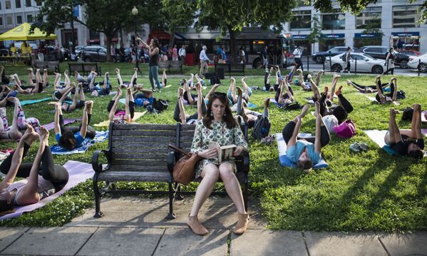Mulher lê um livro durante uma aula coletiva de yoga ao ar livre em Washington, EUA - Sputnik Brasil