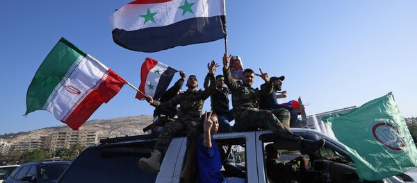 Partidários do governo sírio acenam com bandeiras sírias, iranianas e russas enquanto cantam palavras de ordem contra o presidente norte-americano Trump durante manifestações em Damasco. - Sputnik Brasil