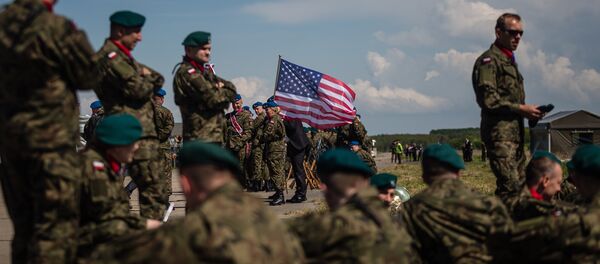 Soldados aguardam cerimônia de abertura da seção norte do escudo antimíssil em base militar na Polônia com bandeira dos EUA no plano de fundo - Sputnik Brasil
