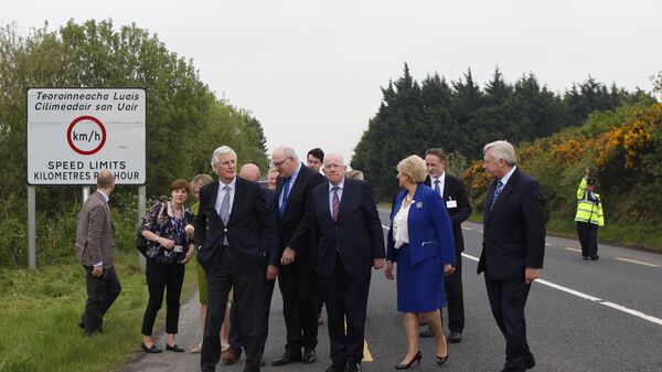 O então negociador-chefe da União Europeia para o Brexit, Michel Barnier (em primeiro plano, à esquerda), e o então ministro das Relações Exteriores irlandês, Charles Flanagan (no centro), caminham pela fronteira irlandesa perto de Castleblayney, na Irlanda, em 12 de maio de 2017 - Sputnik Brasil