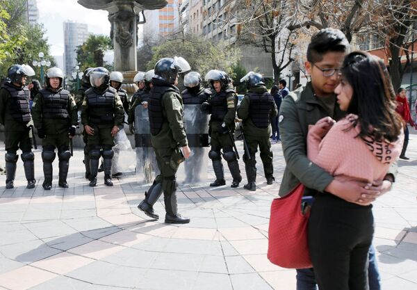 Um casal perto da polícia que está se preparando para os protestos estudantis na Universidade Pública de El Alto (UPEA), Bolívia - Sputnik Brasil