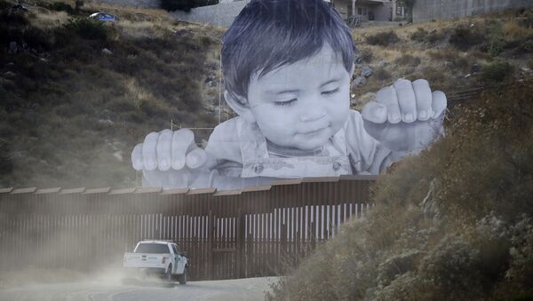 Um veículo da Patrulha da Fronteira dirige em frente a um mural em Tecate, no México, logo depois de uma estrutura fronteiriça. - Sputnik Brasil