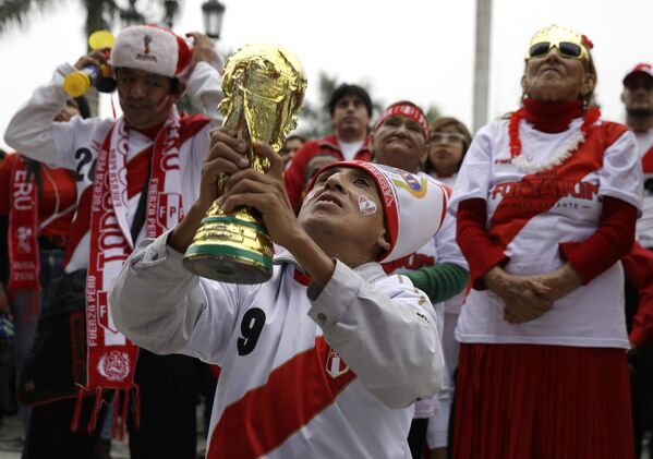 Torcedor peruano ergue réplica da taça da Copa do Mundo enquanto torce na cidade de Lima. - Sputnik Brasil