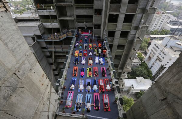Indianos praticando ioga entre duas torres de um edifício residencial em construção por ocasião do Dia Internacional do Ioga, em Ahmadabad, Índia. - Sputnik Brasil