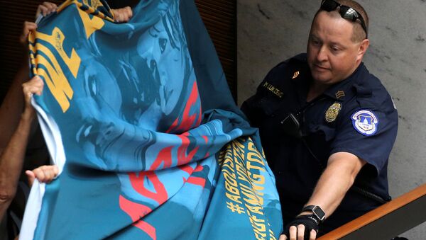 A U.S. Capitol Police officer attempts to take a protest banner from demonstrators calling for an end to family detention and in opposition to the immigration policies of the Trump administration, at the Hart Senate Office Building on Capitol Hill in Washington, U.S. June 28, 2018 - Sputnik Brasil