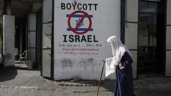 A Palestinian woman walks past a mural calling people to boycott Israeli goods in the al-Azzeh refugee camp near the West Bank city of Bethlehem on September 17, 2014 - Sputnik Brasil