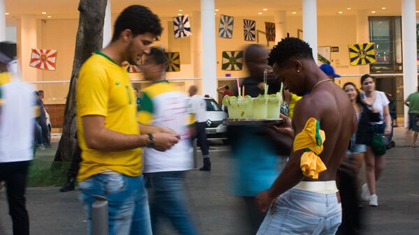 Torcedor compra caipirinha de ambulante durante transmissão do jogo entre Brasil e Bélgica na Praça Mauá, Rio de Janeiro. Centenas de ambulantes vendiam bebidas durante as transmissões. - Sputnik Brasil
