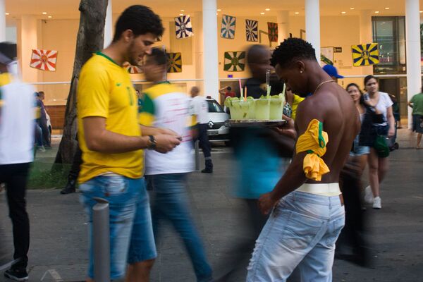 Torcedor compra caipirinha de ambulante durante transmissão do jogo entre Brasil e Bélgica na Praça Mauá, Rio de Janeiro. Centenas de ambulantes vendiam bebidas durante as transmissões. - Sputnik Brasil