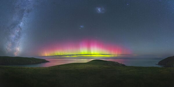 Empírico por Paul Wilson. Águas de Southern Bays (Nova Zelândia) refletem as cores brilhantes rosa e amarela lançadas pela Aurora iluminada. A tonalidade escura de amplos campos verdes e o céu azul-escuro são sombreados por incríveis cores vivas da aurora - Sputnik Brasil