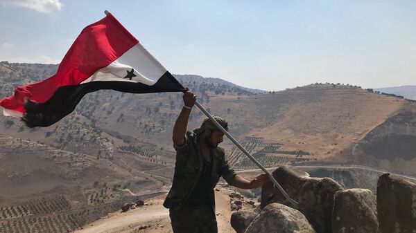 Militar sírio hasteia bandeira da Síria no sudoeste da província de Daraa, na fronteira com a Jordânia - Sputnik Brasil