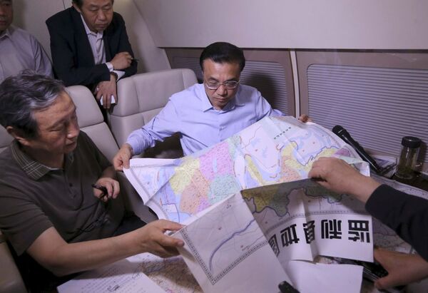 O primeiro-ministro da China, Li Keqiang, no seu avião, olha o mapa da localidade e discute com especialistas o plano de resgate. Em finais de maio, o premiê tinha realizado uma visita ao Brasil. - Sputnik Brasil