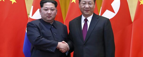 O líder norte-coreano Kim Jong-un, à esquerda, e o presidente chinês Xi Jinping apertam as mãos durante encontro em Pequim. - Sputnik Brasil