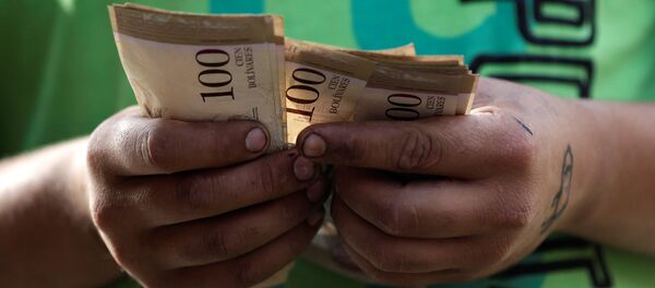 Um caixa conta notas de bolívar venezuelano em um mercado de rua no centro de Caracas, Venezuela (arquivo) - Sputnik Brasil