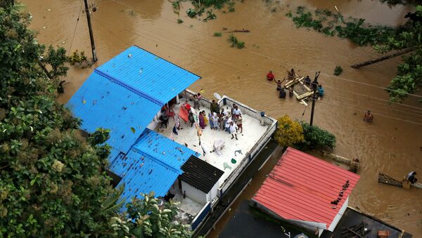 Pessoas esperam por ajuda sobre um telhado após enchente no estado indiano de Kerala - Sputnik Brasil
